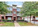 Three-story brick townhome featuring dual balconies, a well-manicured lawn, and an inviting walkway at 1412 W 4Th St, Charlotte, NC 28208