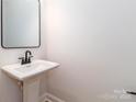 Well-lit bathroom with a pedestal sink, large mirror, and modern fixtures at 2505 Elon St, Charlotte, NC 28208