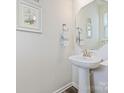 Elegant half bathroom with pedestal sink, decorative mirror, and stylish wall art at 3813 Amalia Pl, Indian Land, SC 29707