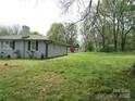 A spacious backyard with mature trees offers a serene setting, complemented by a shed with a red door at 412 E Broad St, Salisbury, NC 28144