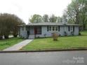 Charming single-story home featuring a red front door, gray brick, and landscaped yard with mature trees at 412 E Broad St, Salisbury, NC 28144
