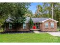Inviting brick home features a well-maintained lawn, mature landscaping and a welcoming red front door at 4989 Post Oak Ln, Rock Hill, SC 29732