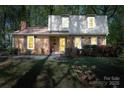 Traditional brick home with a gambrel roof, shuttered windows, and a well-manicured lawn with flowering bushes at 5623 Eastbrook Rd, Charlotte, NC 28215