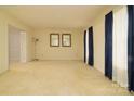 Spacious living room featuring neutral carpeting and light-filled windows at 5623 Eastbrook Rd, Charlotte, NC 28215