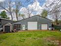 Large metal barn with two garage doors, a separate door, and a small storage shed on a green lawn at 589 Lippard Farm Rd, Statesville, NC 28625