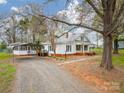Exterior view featuring a white cottage with a metal roof, carport, and gravel driveway at 589 Lippard Farm Rd, Statesville, NC 28625