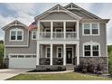 Two-story home with a welcoming front porch, second floor balcony, attached garage, and manicured lawn at 10035 Mast Cove Ln, Charlotte, NC 28278
