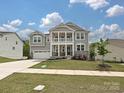 Charming two-story home with a covered porch, gray siding, stone accents, and a well-manicured lawn at 10035 Mast Cove Ln, Charlotte, NC 28278