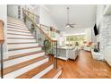 Bright living room featuring a fireplace, hardwood floors, and a staircase with wrought iron details at 114 Misty Meadows Ct, Mooresville, NC 28117