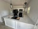 Modern kitchen with quartz counters, island with sink, pendant lights, and sleek black appliances at 1413 Hateras Ave, Charlotte, NC 28216