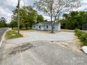 Light blue single-story home with gravel driveway and minimalist landscaping, offering a modern, clean aesthetic at 171 Three Cs Rd, Kershaw, SC 29067