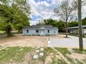 Quaint light-blue home with a well-kept lawn, stone pathway, and large tree shading the gravel parking area at 171 Three Cs Rd, Kershaw, SC 29067