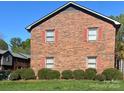 Rear exterior of a brick townhouse with red shutters and manicured shrubbery at 266 Kelly St, Statesville, NC 28677