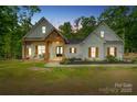 Elegant farmhouse exterior at dusk, featuring a welcoming porch and manicured lawn at 358 Grassy Ridge Ct, Clover, SC 29710
