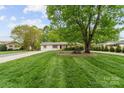 Well-kept front yard showcasing a mature shade tree and a neatly landscaped lawn at 5211 Driftwood Dr, Davidson, NC 28036