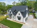 Beautiful two-story modern home featuring a black roof, white brick, well-manicured lawn, and a concrete driveway at 5511 Fairview Rd, Charlotte, NC 28209