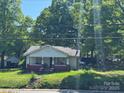 Quaint one-story home featuring a classic front porch design and mature trees providing shade and curb appeal at 1203 N Charlotte Ave, Monroe, NC 28110