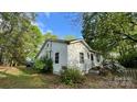 Side view of a quaint home featuring white siding, large windows, and a mature tree in a sunny yard at 2118 Polkville Rd, Shelby, NC 28150