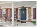 Inviting front porch with brick columns, seating, a decorative wreath, and fresh landscaping at 2856 Huckleberry Hill Dr, Fort Mill, SC 29715
