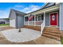 Inviting front porch of gray home, showcasing white gravel and a vibrant red front door at 3659 Kimber Ln, Sherrills Ford, NC 28673