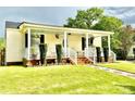 Inviting front porch with decorative hanging plants, white railing, and manicured greenery at 45 Oak St, Great Falls, SC 29055