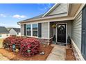 Inviting front porch with black door, stone accents, landscaping, and colorful decorations at 550 Cherry Blossom Nw Ave, Concord, NC 28027