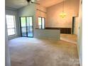 Spacious living room with vaulted ceilings, sliding glass doors to a balcony, and neutral carpeting at 5810 Harris Grove Ln, Charlotte, NC 28212