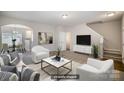 Virtually staged living room with a comfortable seating area and open access to the kitchen and stairway at 9419 Isaac Hunter Dr, Charlotte, NC 28214