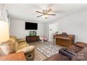 Open-concept living room with neutral walls, laminate flooring, a ceiling fan, and entertainment area at 103 Woodwinds St, Locust, NC 28097