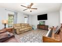 Cozy living room showcasing neutral walls, a ceiling fan, laminate flooring, and natural light from windows at 103 Woodwinds St, Locust, NC 28097
