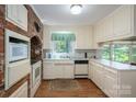 View of the kitchen featuring white cabinets and appliances, exposed brick, and a view of nature through the window at 1058 General Hoke Dr, Lincolnton, NC 28092