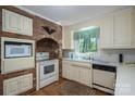 Traditional kitchen featuring brick accents, white appliances, ample cabinet space and a bright window at 1058 General Hoke Dr, Lincolnton, NC 28092