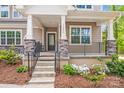 Close up view of front porch with stone pillar bases, black metal railing, and attractive landscaping at 11215 Dappled Light Trl, Charlotte, NC 28227