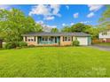 Charming single-story home with a lush front lawn, brick accents, and an attached garage at 1204 Meadowood Dr, Shelby, NC 28150
