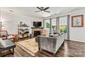 Comfortable living room featuring a ceiling fan, stone fireplace, large windows, and hardwood flooring at 158 Bluffton Rd, Mooresville, NC 28115