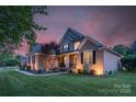 Elegant brick home with a lush green lawn, complemented by a twilight sky and landscape lighting at 1614 Crestgate Dr, Waxhaw, NC 28173