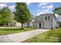 Landscaped front yard with a long driveway leading to a gray two-story home featuring an attached garage and well-maintained lawn at 1911 Almond Hills Dr, Charlotte, NC 28262