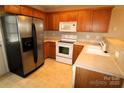 Well-lit kitchen with stainless steel refrigerator, white appliances, and wooden cabinets offering ample storage at 2043 Shady Pond Dr, Clover, SC 29710