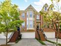 Brick townhome featuring an attached garage, stoop entry, black iron railings, bay window, and mature landscaping at 2621 Huntman Way, Charlotte, NC 28226