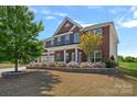 Beautiful brick home boasts lush landscaping with vibrant flowers and a well-maintained lawn at 9867 Travertine Trl, Davidson, NC 28036