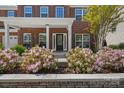 Inviting front porch with vibrant pink flowers, lush plants, and a charming seating area at 9867 Travertine Trl, Davidson, NC 28036