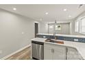 Open-concept kitchen with stainless steel dishwasher, white cabinets, and a bar overlooking the living area at 109 W Poplar St, Stanley, NC 28164