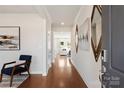 Inviting hallway with hardwood floors, decorative mirrors, modern artwork, and a view into the living area at 117 Vaquaro Dr, Mooresville, NC 28115
