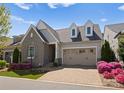 Charming home boasts stone accents, dormer windows, and a well-manicured front yard with colorful flowers at 17728 Jetton Green Loop, Cornelius, NC 28031