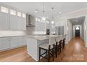 Modern kitchen with stainless steel appliances, pendant lighting, large island with seating, and hardwood floors at 17728 Jetton Green Loop, Cornelius, NC 28031