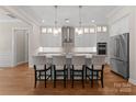 Modern kitchen with stainless steel appliances, pendant lighting, large island with seating, and hardwood floors at 17728 Jetton Green Loop, Cornelius, NC 28031
