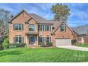 Traditional two-story brick home featuring a manicured lawn, attached garage, and charming front entryway at 213 Walnut Point Dr, Matthews, NC 28105