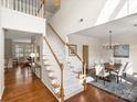 Bright foyer featuring hardwood floors, white staircase with wood banister, leading to an open dining area at 213 Walnut Point Dr, Matthews, NC 28105