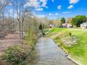 Scenic waterfront view featuring lush green grass and a variety of trees on a sunny day at 32 Heritage Ln, Shelby, NC 28150