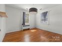 Neutral bedroom featuring hardwood floors, bright windows with neutral curtains and a modern drum shade light fixture at 343 Wakefield Dr # C, Charlotte, NC 28209